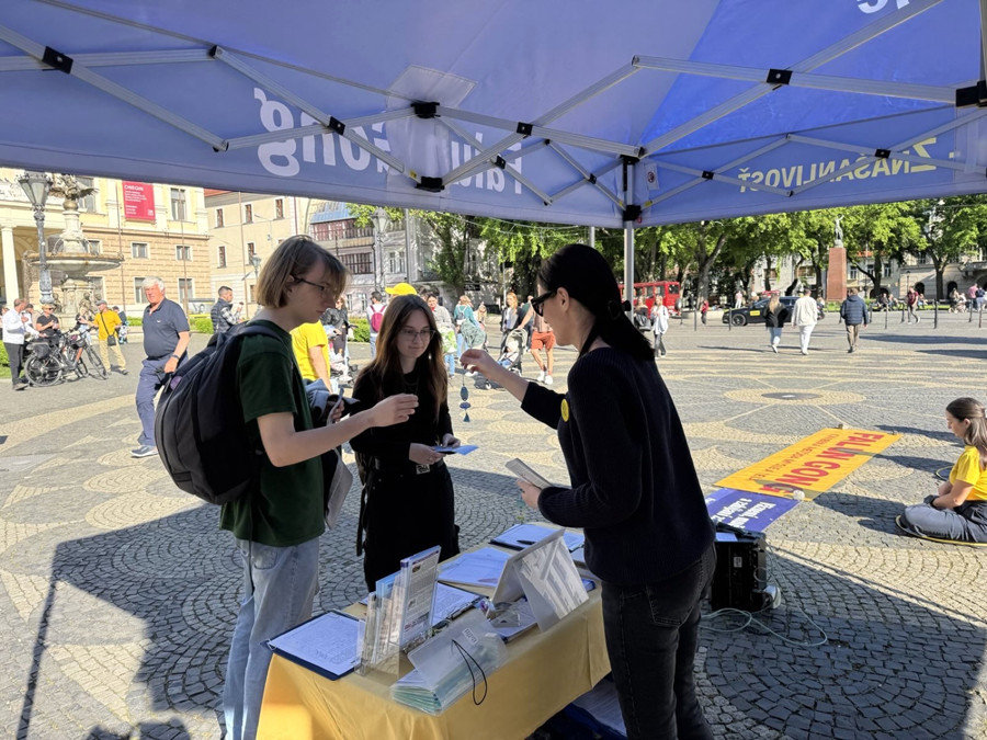 Les passants prennent des documents d'information et une fleur de lotus au stand de pétition