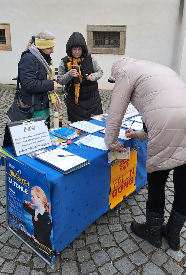 Kolemjdoucí podepisují petici proti pronásledování Kolemjdoucí podepisují petici proti pronásledování