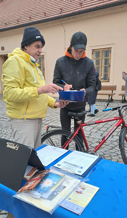 Kolemjdoucí podepisují petici proti pronásledování Kolemjdoucí podepisují petici proti pronásledování