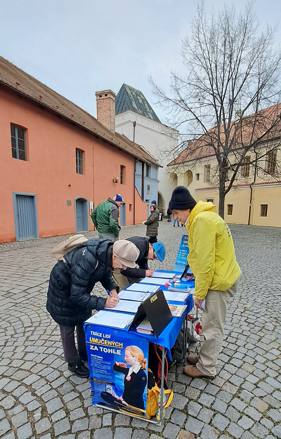 Kolemjdoucí podepisují petici proti pronásledování Kolemjdoucí podepisují petici proti pronásledování