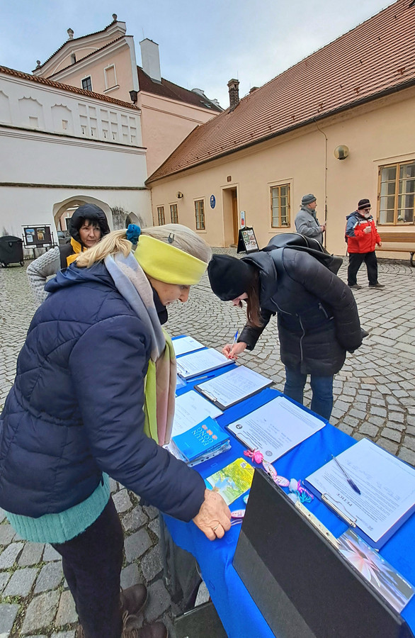 Kolemjdoucí podepisují petici proti pronásledování Kolemjdoucí podepisují petici proti pronásledování